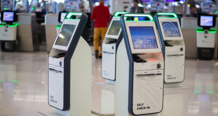 Passengers Using Self Check In Kiosks At Airport With Biometric Verification System