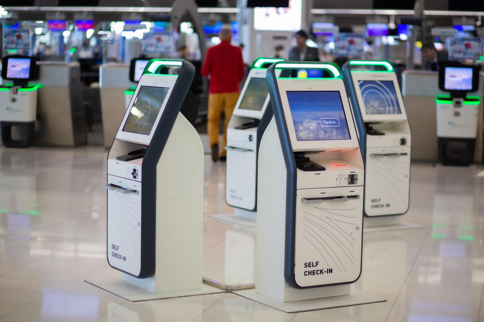 Passengers using self check in kiosks at airport with biometric verification system